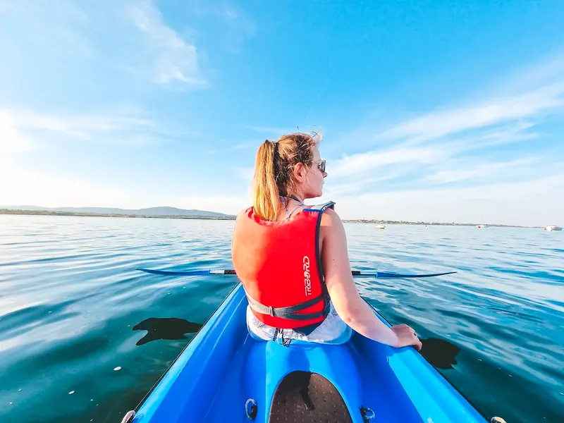 A paddler looks back from a blue kayak on the lagoon